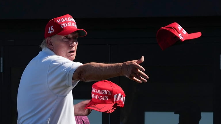 Former President Donald Trump throws autographed hats to the crowd...