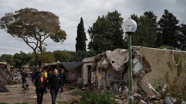 People walk past houses destroyed during the cross-border attack by...