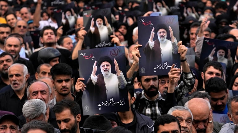 People hold up posters of President Ebrahim Raisi during a...