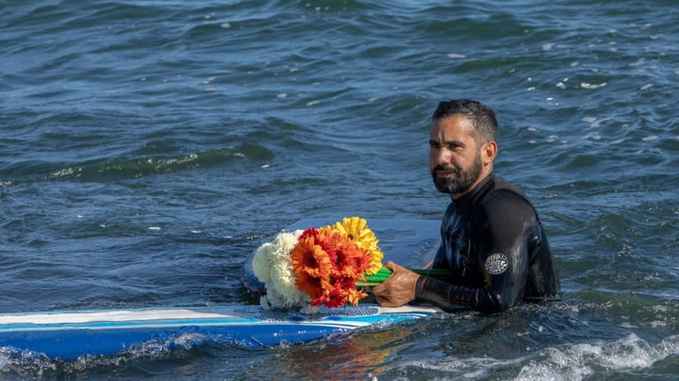 A man holds flowers during a tribute to 3 missing...