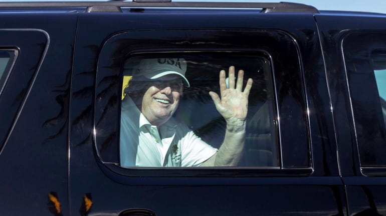 President Donald Trump waves to supporters as he travels to...