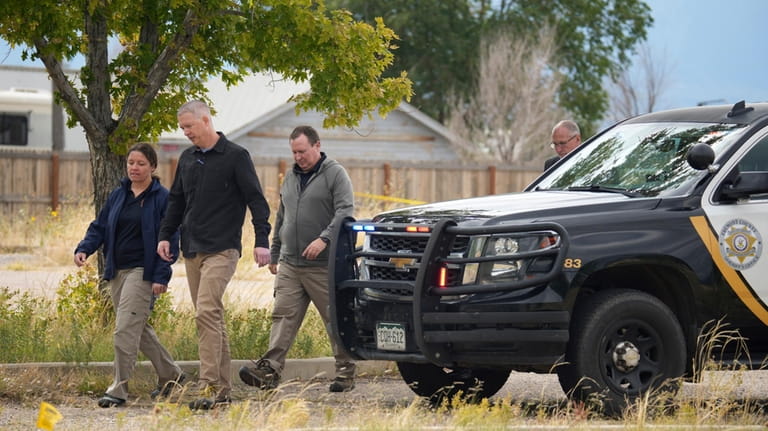 Authorities walk outside a closed funeral home where multiple bodies...