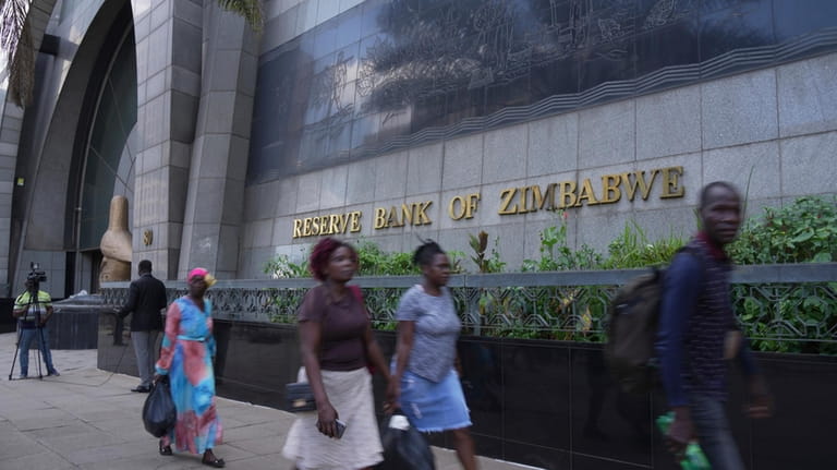 People walk past the Reserve Bank of Zimbabwe following the...