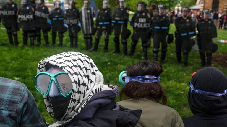 A pro-Palestinian demonstrator wears goggles and a mask as police...