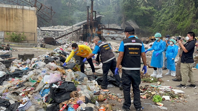 Thai police forensic officers investigate a garbage dump site as...