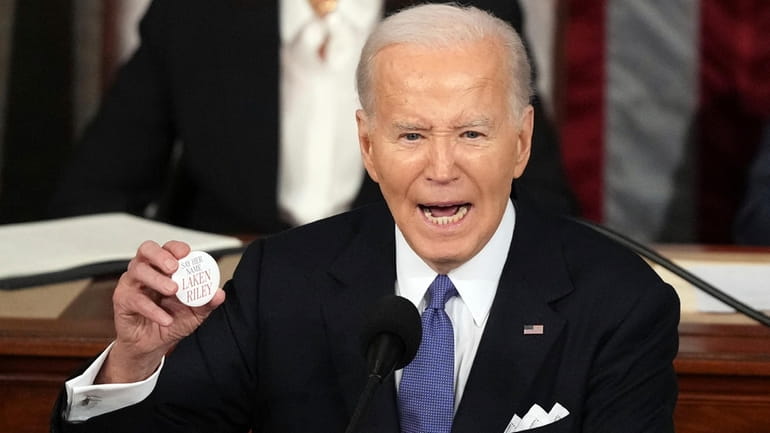 President Joe Biden holds up a Laken Riley Botton as...