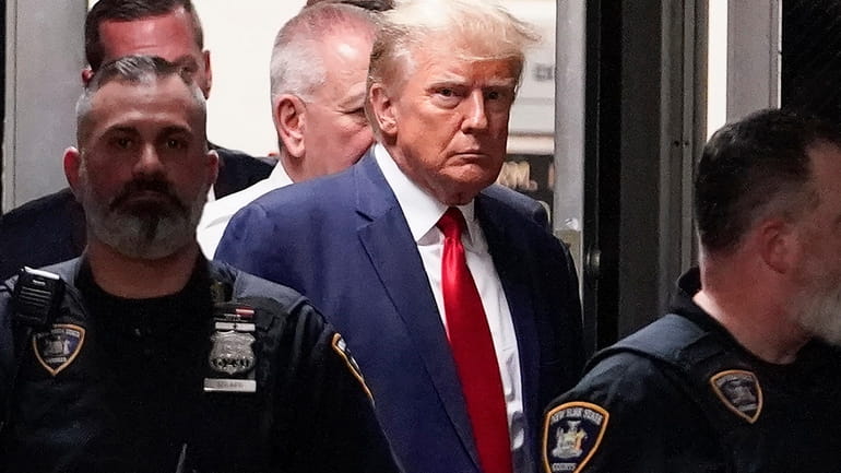 Former President Donald Trump is escorted to a courtroom in...