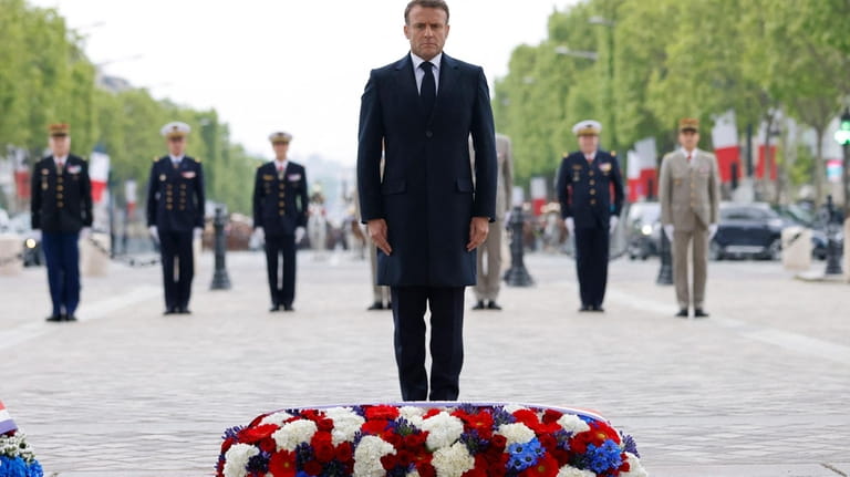 French President Emmanuel Macron stands after laying a wreath of...