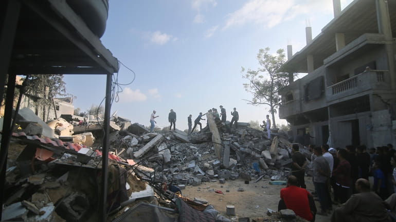 Palestinians stand by the building destroyed in an Israeli airstrike...
