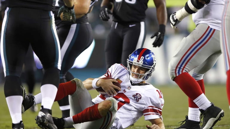 Giants quarterback Eli Manning lays on the ground after a...