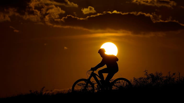 A cyclist tops a hill on a hot day at...
