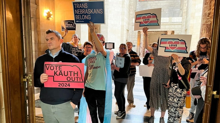 Protesters hold signs outside the doors of the legislative chamber...