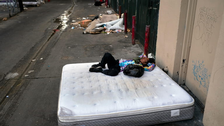 A homeless man sleeps on a discarded mattress in Los...