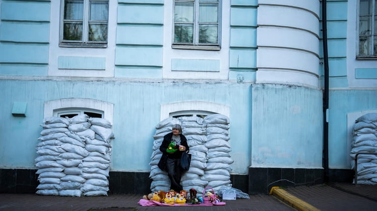 A woman sells toys in front of a building with...