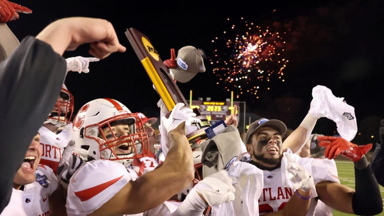 Cortland players celebrate with the trophy after a win over...