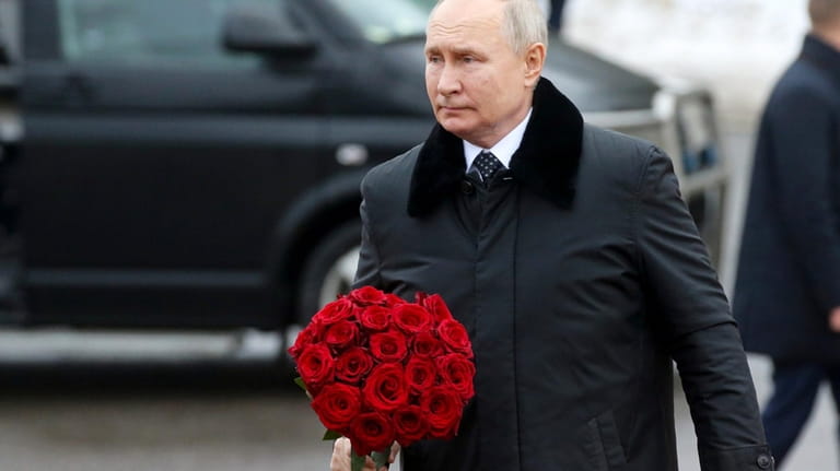 Russian President Vladimir Putin walks to place flowers on a...