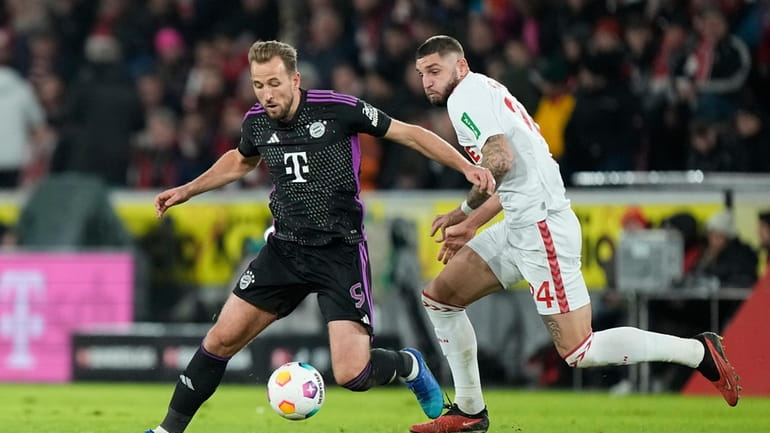 Bayern's Harry Kane, left, challenges for the ball with Cologne's...