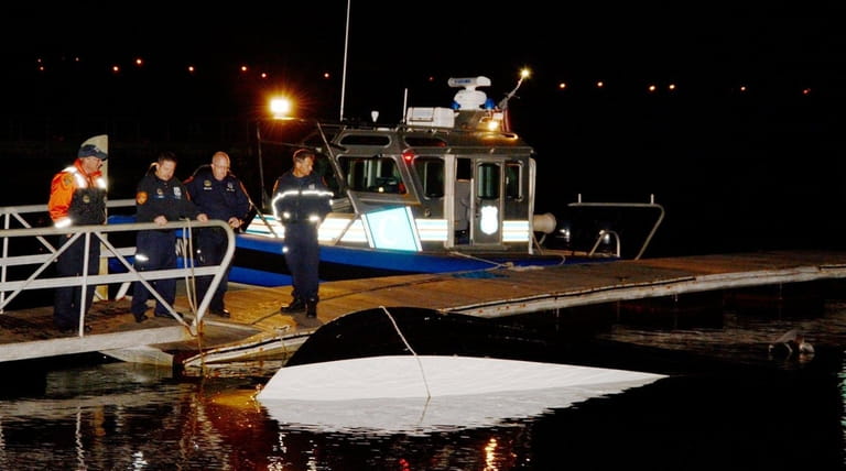Suffolk Marine Bureau and other officers investigate an overturned boat...