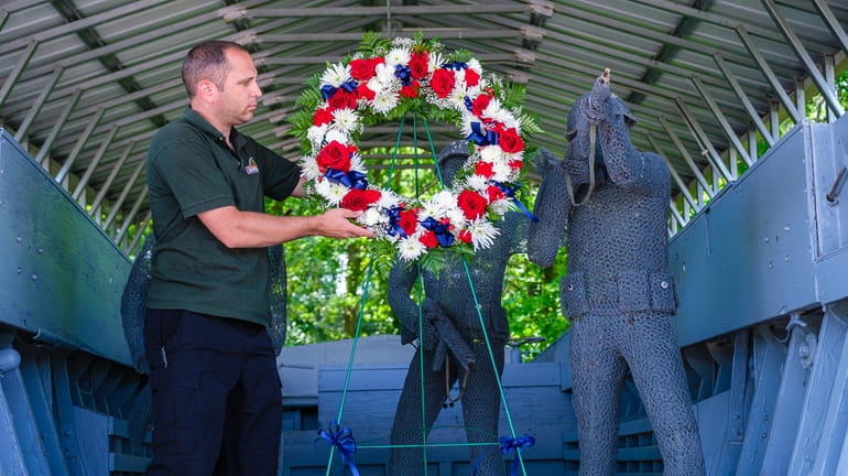 Volunteer Shane Ekberg displays the wreath, in memory of those...