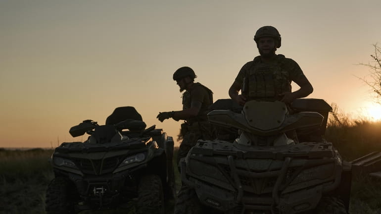 Ukrainian soldiers ride all-terrain vehicles at the front line near...