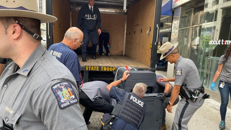 Authorities load a copy machine into a State Police truck...
