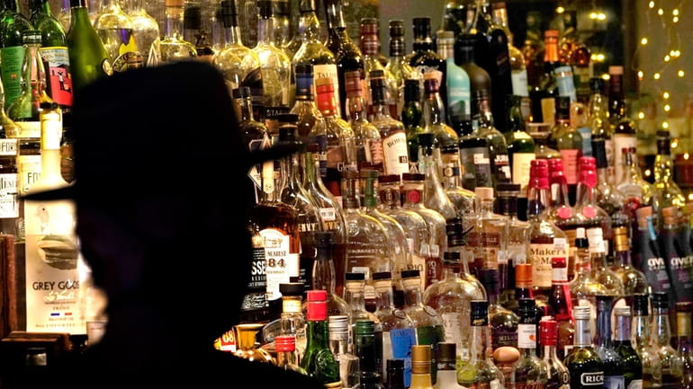 Bottles of alcohol sit on shelves at a bar in...