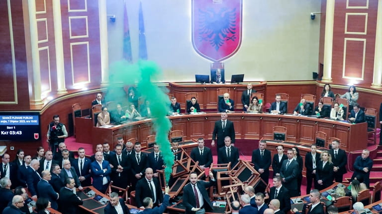 Democratic lawmakers throw flares during a parliament session in Tirana,...