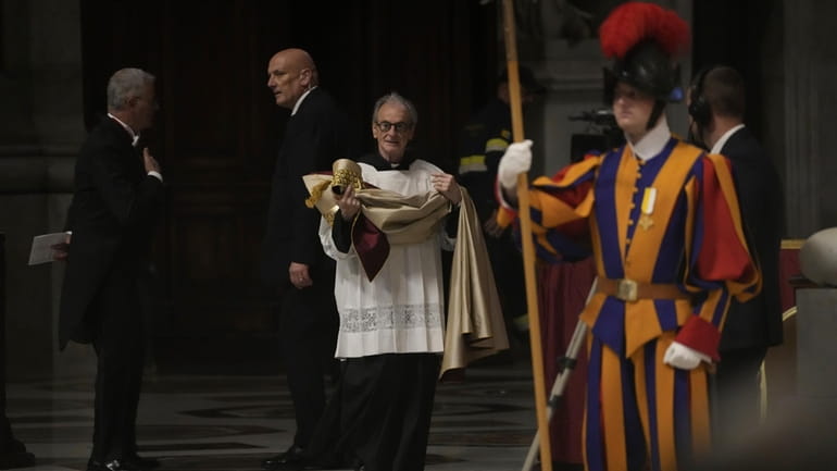 A deacon brings the papal robe for Pope Francis who...
