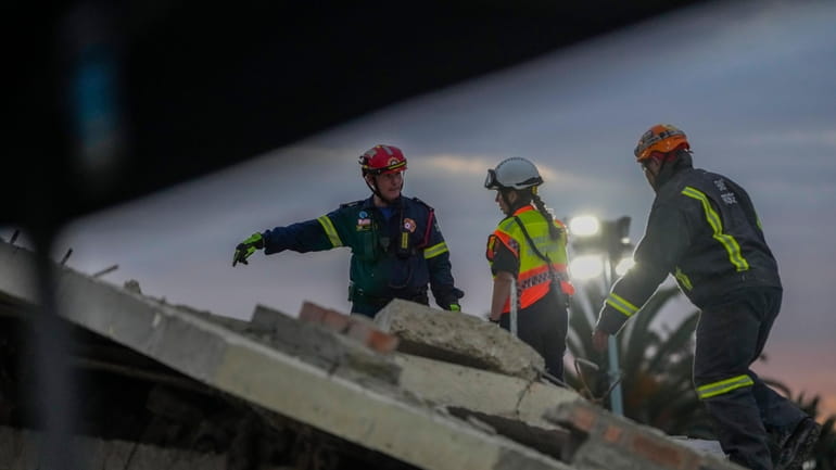 Rescue workers search the site of a building collapse in...