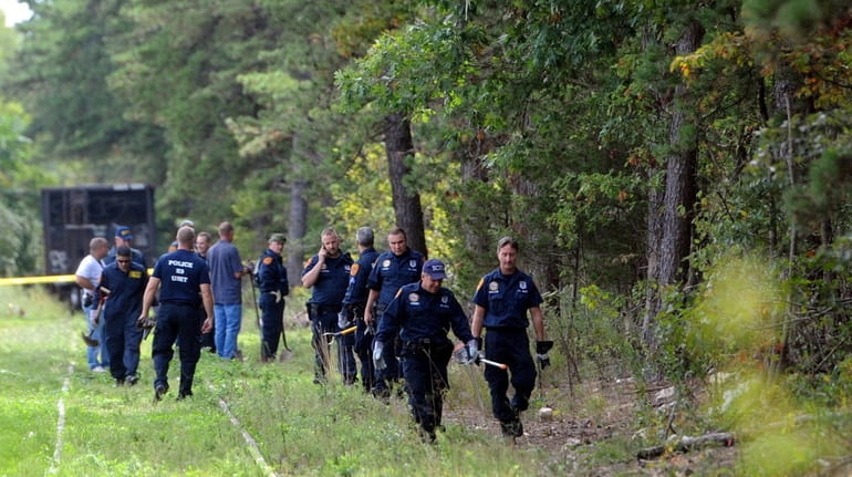 Suffolk County police investigators probe a wooded area in Brentwood...