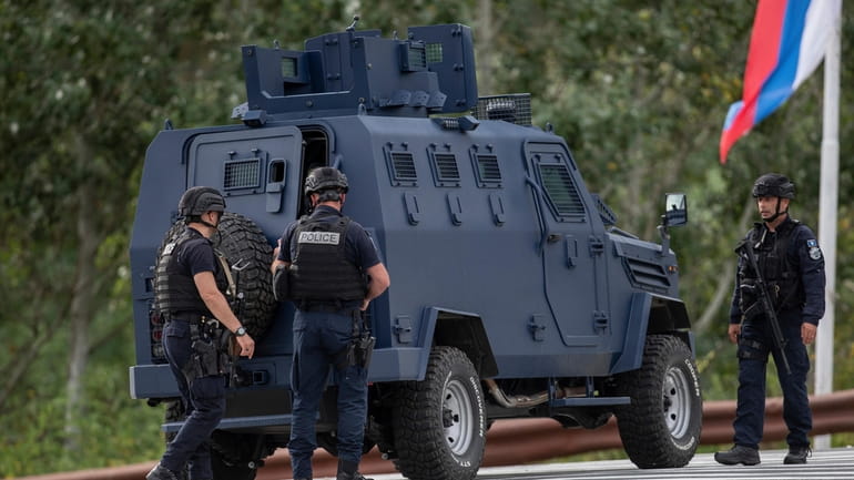 Kosovo police officers seen near an armored vehicle secure a...