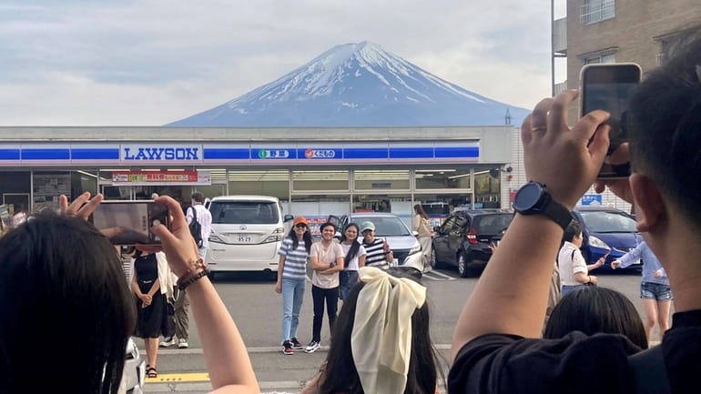 Visitors take a photo in front of a convenient store...