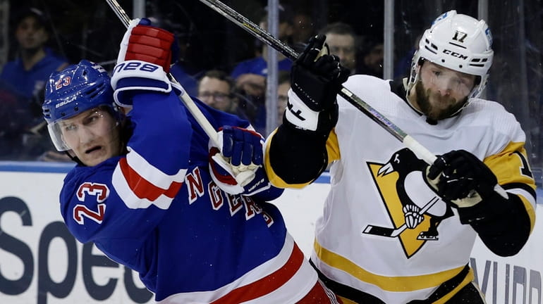 Adam Fox of the Rangers and Bryan Rust of the Penguins battle for...