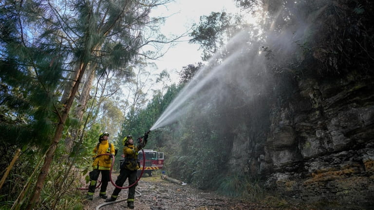 Firefighters work to control a forest fire on El Cable...