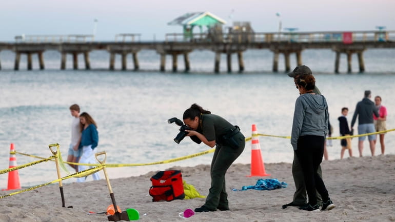 Investigators on the beach in Lauderdale-by-the-Sea, Fla., take photos of...