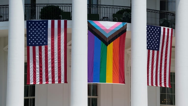 American flags and a pride flag hang from the White...
