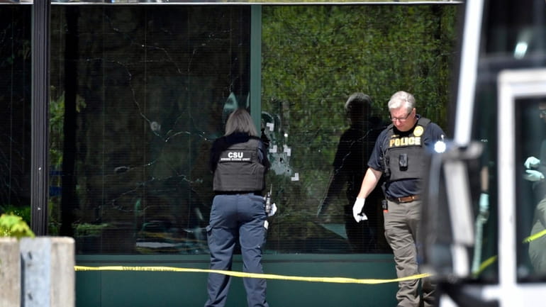 Louisville police personnel photograph bullet holes in the glass of the...
