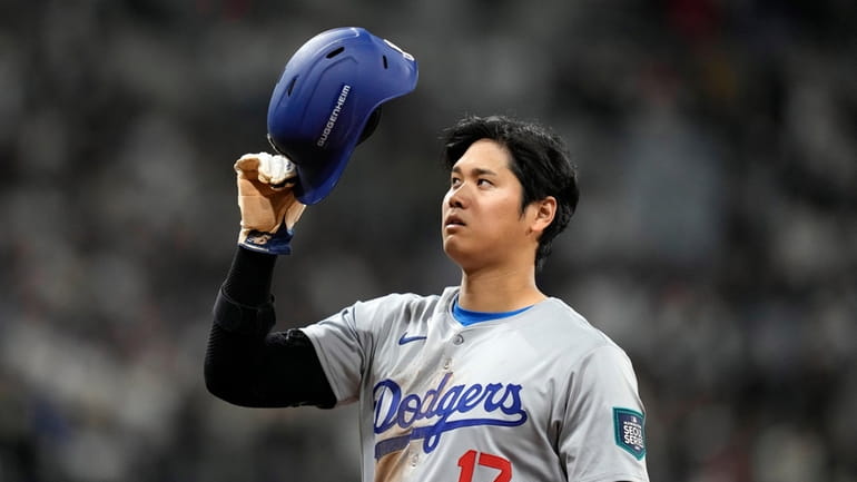 Los Angeles Dodgers designated hitter Shohei Ohtani takes his helmet...