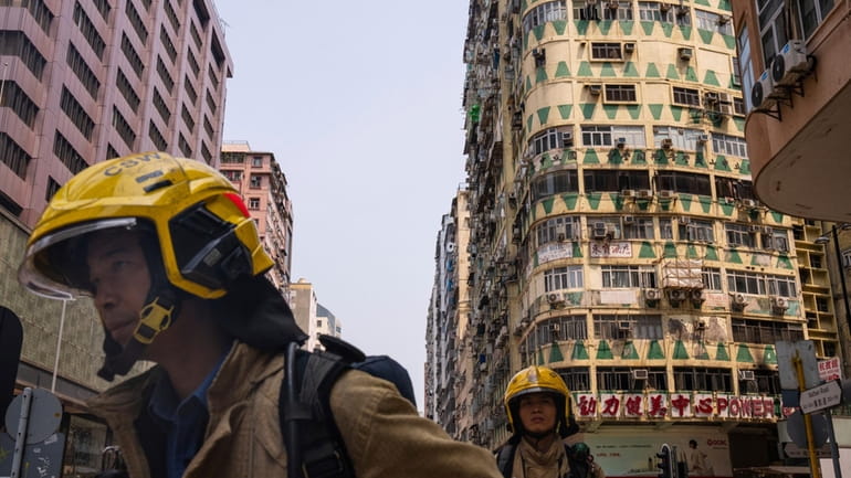 Firefighters walk past a building called New Lucky House where...