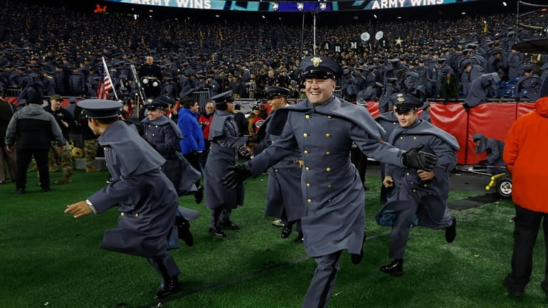 Army Cadets storm the field after defeating Navy in an...