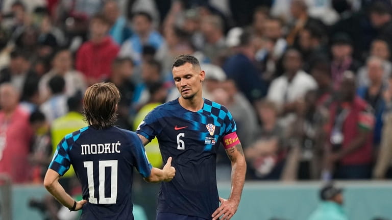 Croatia's Luka Modric, left, and Croatia's Dejan Lovren shake hands...