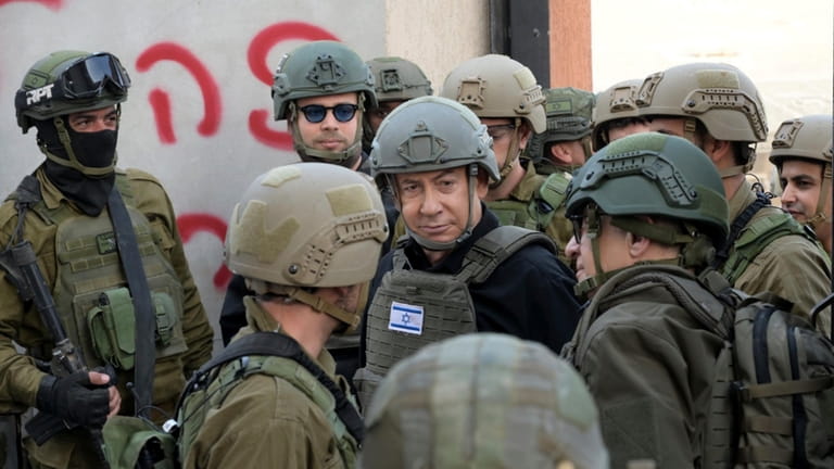 Israeli Prime Minister Benjamin Netanyahu, center, wears a protective vest...