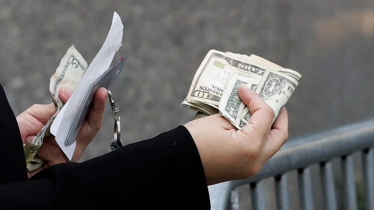 A woman pays with cash as she buys from a...