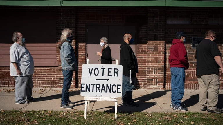 Voters wait in line outside a polling center on Election...