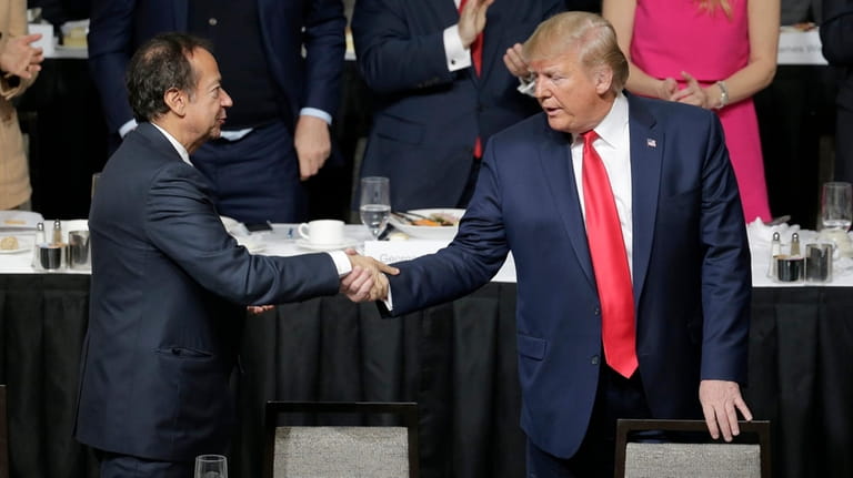 President Donald Trump, right, shakes hands with John Paulson during...