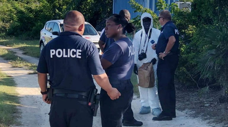 Turks and Caicos Islands Police Force officers investigate the death...