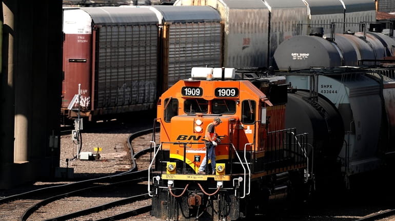 A worker boards a locomotive at a BNSF rail yard...