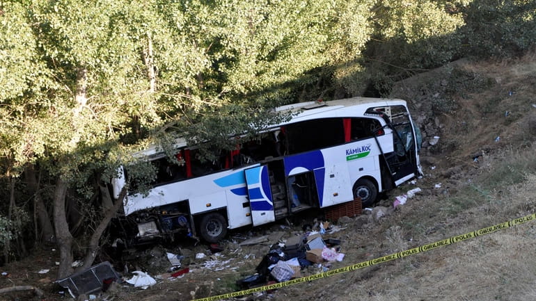 Officials investigate at the site of a bus crash in...