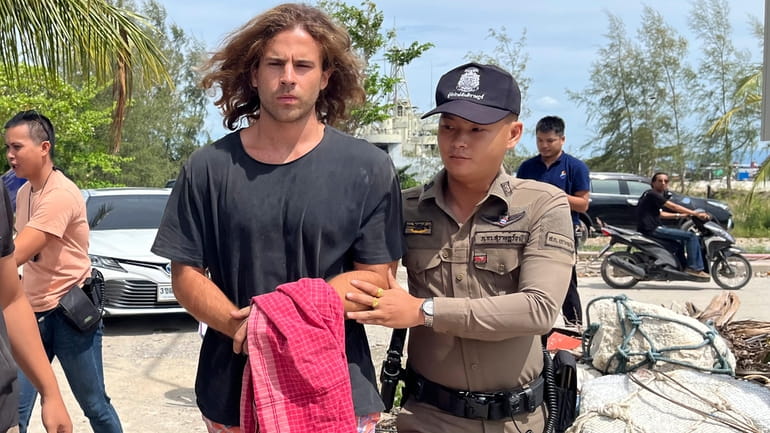 A Thai police officer escorts Spanish Daniel Sancho Bronchalo on...