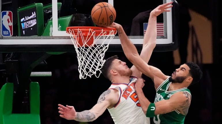 New York Knicks center Isaiah Hartenstein, left, blocks a shot...